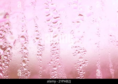Deilcate Regentropfen Wasser auf Glas in einem rosa Glow für Hintergrund Stockfoto