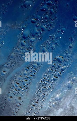 Deilcate Regentropfen Wasser auf Glas in einem blauen Glow für Hintergrund Stockfoto