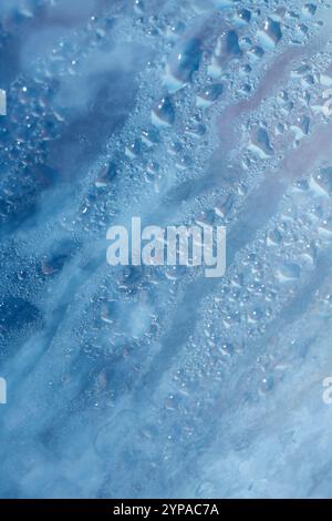 Deilcate Regentropfen Wasser auf Glas in einem blauen Glow für Hintergrund Stockfoto