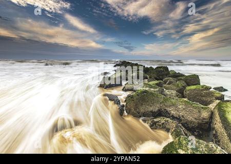 Surfwasser an einer Steinkippe an der Nordseeküste, Niederlande, Texel, Duenen von Texel Nationalpark Stockfoto