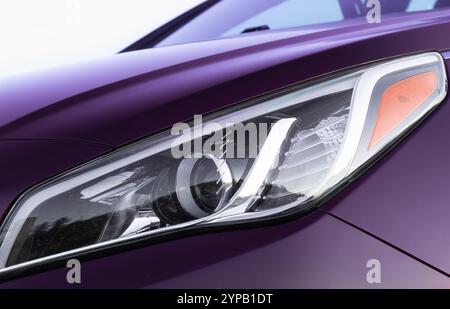 Vorderansicht der LED-Scheinwerfer des Sportwagens. Nahaufnahme der Scheinwerferdetails eines modernen Luxussportwagens. Scheinwerfer und Motorhaube des purpurpurnen Sportwagens. Fahrzeugdetails. Stockfoto