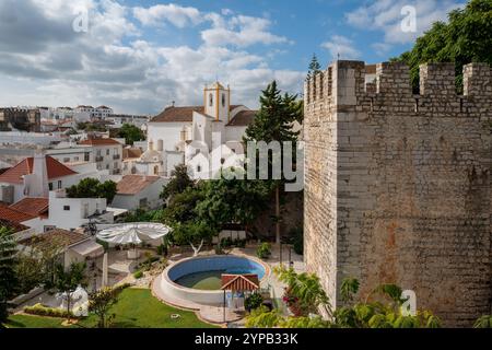 Blick auf die Kirche (Igreja Paroquial de Santiago) und die Burgmauern im November Sonnenschein im beliebten Wintersonnenziel Tavira, Algarve, Portugal Stockfoto