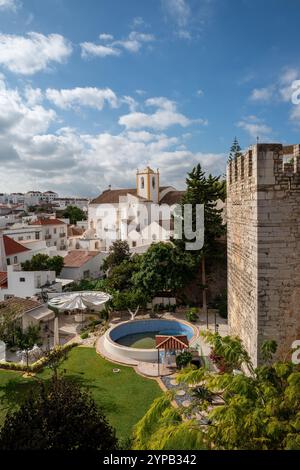 Blick auf die Kirche (Igreja Paroquial de Santiago) und die Burgmauern im November Sonnenschein im beliebten Wintersonnenziel Tavira, Algarve, Portugal Stockfoto