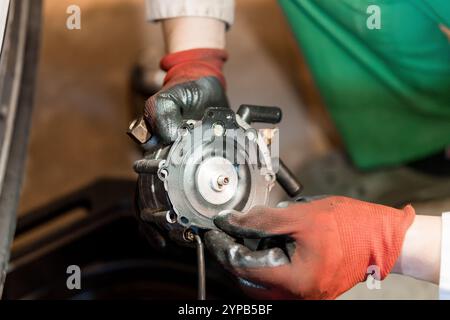 Nahaufnahme eines Technikers, der eine mechanische Komponente in einer Werkstatt hält Stockfoto