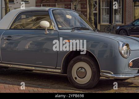 Nahaufnahme eines alten Nissan Figaro blauen Retro-Autos, der auf der Straße geparkt ist Stockfoto