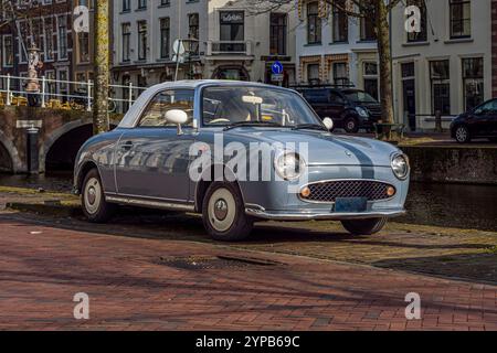 Blaues Retro-Auto von Nissan Figaro parkte an einem sonnigen Tag auf der Straße Stockfoto