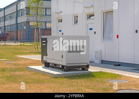 Notstromgenerator im Bereitschaftszustand hinter dem Industriegebäude Stockfoto