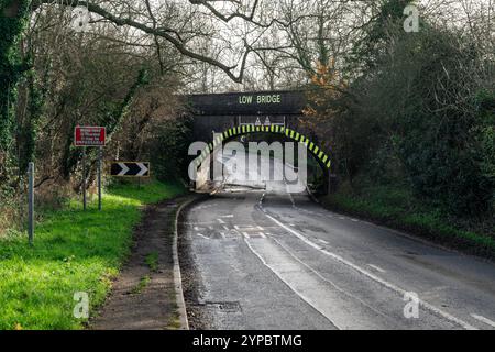 Warnschild für niedrige Brücken und Gefahrenmarkierungen auf einer schmalen Landstraße in großbritannien Stockfoto