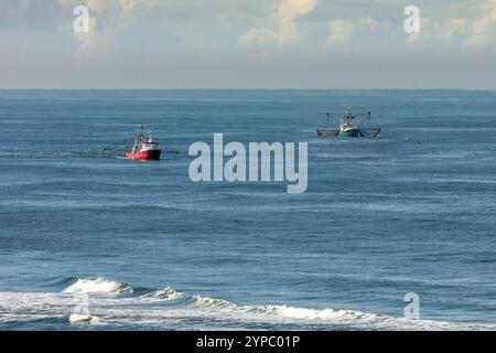Zwei Cutter, einer mit angehobenen Schleppnetzen auf dem blauen Wasser der Nordsee in Strandnähe Stockfoto
