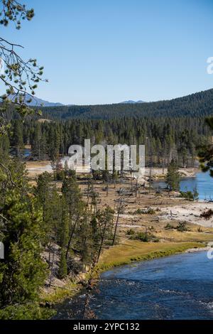 Eine aktive Geysirquelle neben einem Fluss, mit einem intermittierenden Abfluss von Wasser, das turbulent ausgestoßen wird und von Dampf begleitet wird Stockfoto