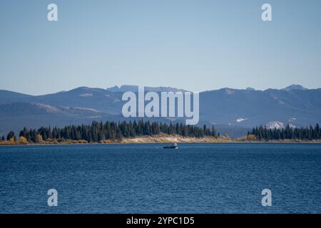 Ein kleines Fischerboot in einem dunkelblauen Wasser See, Wald und Berge Hintergrund Stockfoto