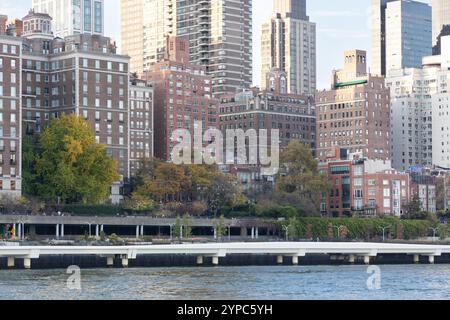 Eine lebhafte Stadtlandschaft zeigt eine Mischung aus klassischer und moderner Architektur entlang des Flusses. Bäume mit Herbstfarben sorgen für Wärme Stockfoto