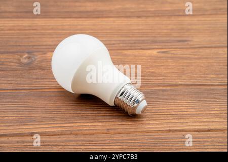 Dies ist ein Nahbild einer LED-Glühlampe, die auf einer Holzoberfläche liegt Stockfoto