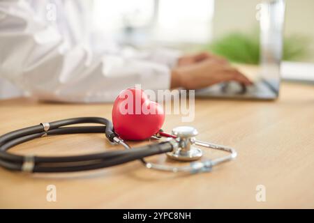 Stethoskop und rotes Herz auf dem Schreibtisch mit Arzt Kardiologe vor Hintergrund. Kardiologie und Gesundheitswesen Stockfoto