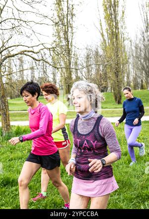 Gruppe von Frauen, die im Frühling zügig in einem grünen Park spazieren gehen. Konzentrieren Sie sich auf einen aktiven und gesunden Lebensstil, mit verschiedenen Frauen, die Sport im Freien genießen Stockfoto