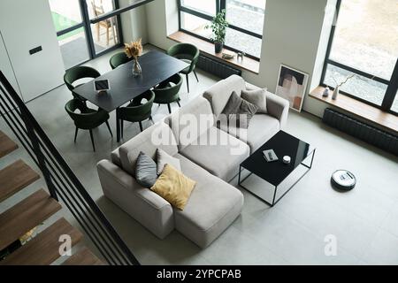 Geräumiges, modernes Wohnzimmer mit gemütlichem Sofa mit Kissen und angrenzendem Essbereich. Tageslicht, das durch große Fenster einströmt, schafft ein helles Ambiente Stockfoto
