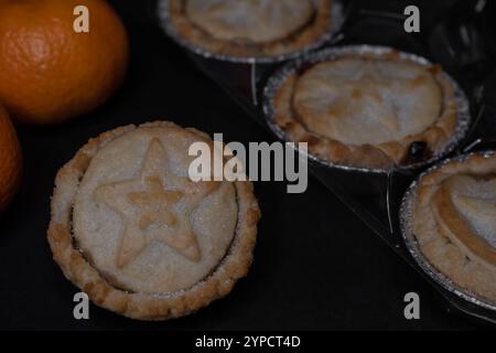 Zitrusfrüchte und frisch gebackene Hackkuchen mit Sternsymbol auf dunklem Hintergrund Stockfoto