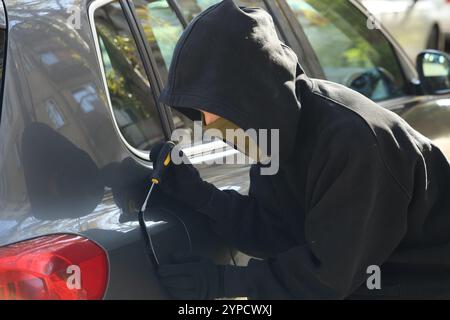 Dieb mit Schraubendreher zum Öffnen des Tankdeckels. Autoentführung Stockfoto