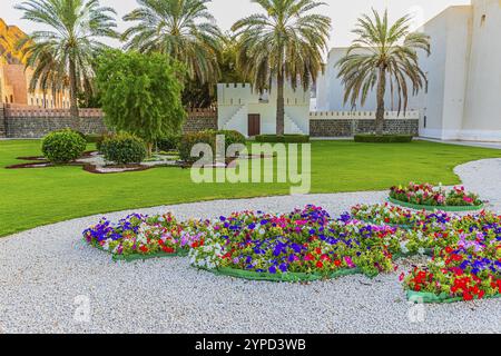 Park mit Schotterwegen, Blumen und Palmen am Sultanspalast, Muskat, Arabische Halbinsel, Sultanat Oman Stockfoto