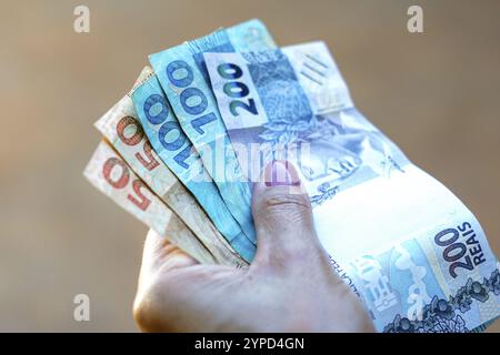 April 2024, Brasilien. Die Frau hält etwa fünfzig, einhundertzweihundert Reais-Scheine, brasilianisches Geld. Laut offiziellen Daten ist der durchschnittliche Hous Stockfoto