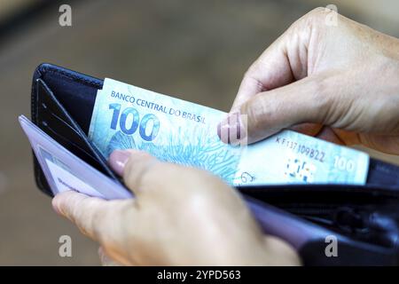 April 2024, Brasilien. Eine Frau hat eine 100 (100) Reais-Note in ihrer Brieftasche. Laut offiziellen Daten ist das durchschnittliche Haushaltseinkommen pro kapitel Stockfoto