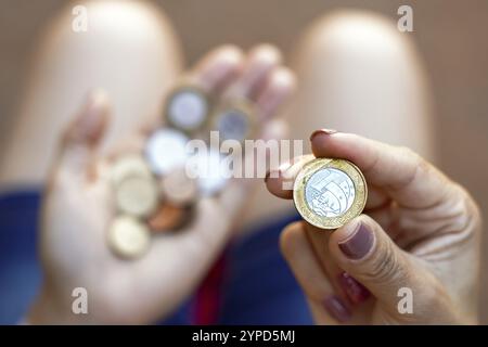 April 2024, Brasilien. Die Frau hält ein paar echte Münzen, brasilianisches Geld. Amtlichen Daten zufolge ist das durchschnittliche Haushaltseinkommen pro Kopf (pro Person) Stockfoto