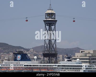 Seilbahn über dem Hafen, dominiert von einem hohen Turm vor einer städtischen Kulisse, barcelona, spanien Stockfoto