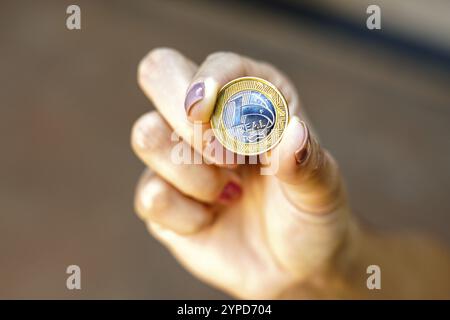 April 2024, Brasilien. Die Frau hält ein paar echte Münzen, brasilianisches Geld. Amtlichen Daten zufolge ist das durchschnittliche Haushaltseinkommen pro Kopf (pro Person) Stockfoto