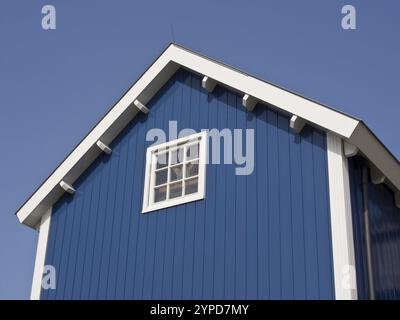 Holzhaus in Blau mit Giebeldach und weiß gerahmtem Fenster vor klarem Himmel, hoorn, ijsselmeer, niederlande Stockfoto