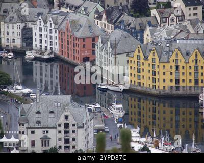 Farbenfrohe Häuser spiegeln sich in einem ruhigen Kanal mit Booten, alesund, norwegen Stockfoto