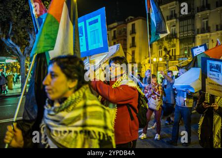 Logroño, La Rioja, Spanien. November 2024. Pro-palästinensische Aktivisten unterbrechen die offizielle Weihnachtsbeleuchtung in Logroño. Mit Kerzen, palästinensischen Fahnen und symbolischen Särgen stehen sie hinter der Bürgermeisterprozession. Ihr stiller Protest zielt darauf ab, den Konflikt in Gaza sichtbar zu machen und einen festlichen Moment in einen Raum für Denunziation und Reflexion über die humanitäre Krise in Palästina zu verwandeln. Quelle: Mario Martija/Alamy Live News. Stockfoto