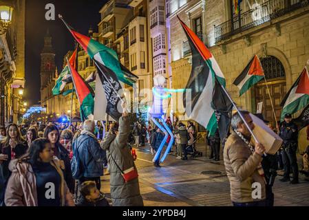 Logroño, La Rioja, Spanien. November 2024. Pro-palästinensische Aktivisten unterbrechen die offizielle Weihnachtsbeleuchtung in Logroño. Mit Kerzen, palästinensischen Fahnen und symbolischen Särgen stehen sie hinter der Bürgermeisterprozession. Ihr stiller Protest zielt darauf ab, den Konflikt in Gaza sichtbar zu machen und einen festlichen Moment in einen Raum für Denunziation und Reflexion über die humanitäre Krise in Palästina zu verwandeln. Quelle: Mario Martija/Alamy Live News. Stockfoto