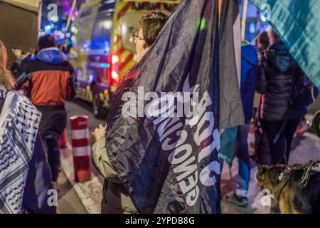 Logroño, La Rioja, Spanien. November 2024. Pro-palästinensische Aktivisten unterbrechen die offizielle Weihnachtsbeleuchtung in Logroño. Mit Kerzen, palästinensischen Fahnen und symbolischen Särgen stehen sie hinter der Bürgermeisterprozession. Ihr stiller Protest zielt darauf ab, den Konflikt in Gaza sichtbar zu machen und einen festlichen Moment in einen Raum für Denunziation und Reflexion über die humanitäre Krise in Palästina zu verwandeln. Quelle: Mario Martija/Alamy Live News. Stockfoto