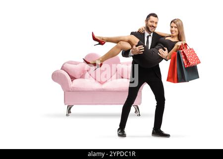 Mann, der eine Frau mit Einkaufstaschen in den Händen trägt, isoliert auf weißem Hintergrund Stockfoto