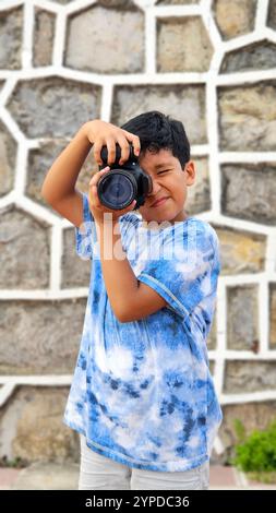 Der 10-jährige dunkelhäutige Latino Boy lernt eine professionelle Kamera zu benutzen, träumt und stellt sich vor, als Erwachsener zu arbeiten Stockfoto