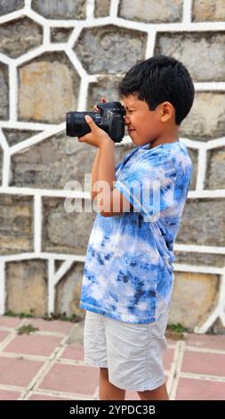 Der 10-jährige dunkelhäutige Latino Boy lernt eine professionelle Kamera zu benutzen, träumt und stellt sich vor, als Erwachsener zu arbeiten Stockfoto