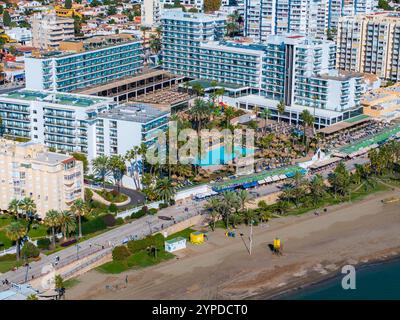 Blick aus der Vogelperspektive auf Benalmadena, Spanien, mit modernen Hotels, einem Poolbereich mit Palmen, einem Sandstrand mit Promenade und einer urbanen Landschaft im Ba Stockfoto