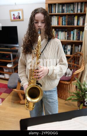 Teenagermädchen spielt Saxophon im Wohnzimmer Stockfoto