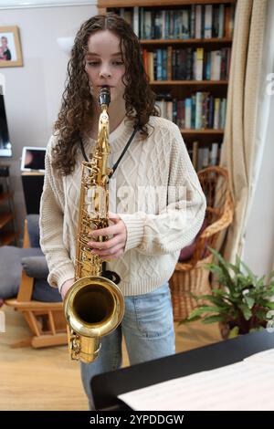 Teenagermädchen spielt Saxophon im Wohnzimmer Stockfoto