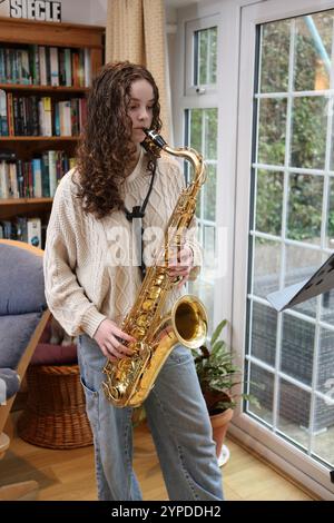 Teenagermädchen spielt Saxophon im Wohnzimmer Stockfoto