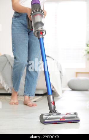 Frau, die den Boden mit schnurlosem Staubsauger in Innenräumen reinigt, Nahaufnahme Stockfoto