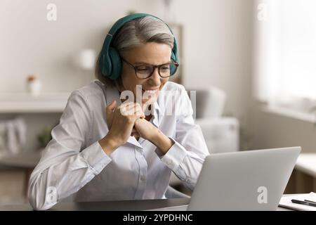 Fröhliche Geschäftsfrau mittleren Alters, die am Laptop arbeitet Stockfoto