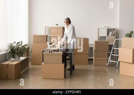 Beschäftigte kleine E-Commerce-Lagerarbeiterin, die Paketcontainer hält Stockfoto
