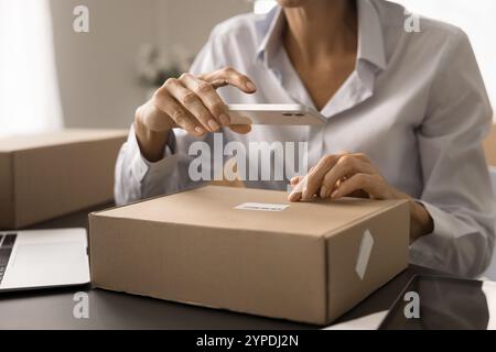 Reife E-Commerce-Speicherarbeiterin, die ein Mobiltelefon benutzt Stockfoto