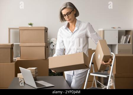 Reife E-Commerce-Lagerarbeiterin, die ein Paket hält Stockfoto