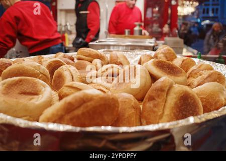 Ein großes Tablett mit goldbraunen, frisch gebackenen Brötchen an einem belebten Weihnachtsmarkt aus der Nähe. Stockfoto