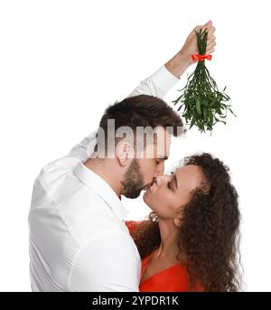 Ein glückliches Paar küsst sich unter Mistelzweigen auf weißem Hintergrund Stockfoto