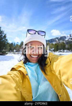 POV einer afroamerikanischen jungen Frau, die Selfie mit zwei Händen mit dem Handy in verschneiten Bergen macht. Stockfoto