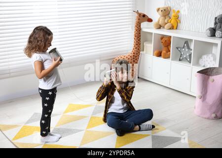 Junge und Mädchen reden über Blechdose telefonieren drinnen Stockfoto