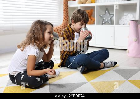 Junge und Mädchen reden über Blechdose telefonieren drinnen Stockfoto